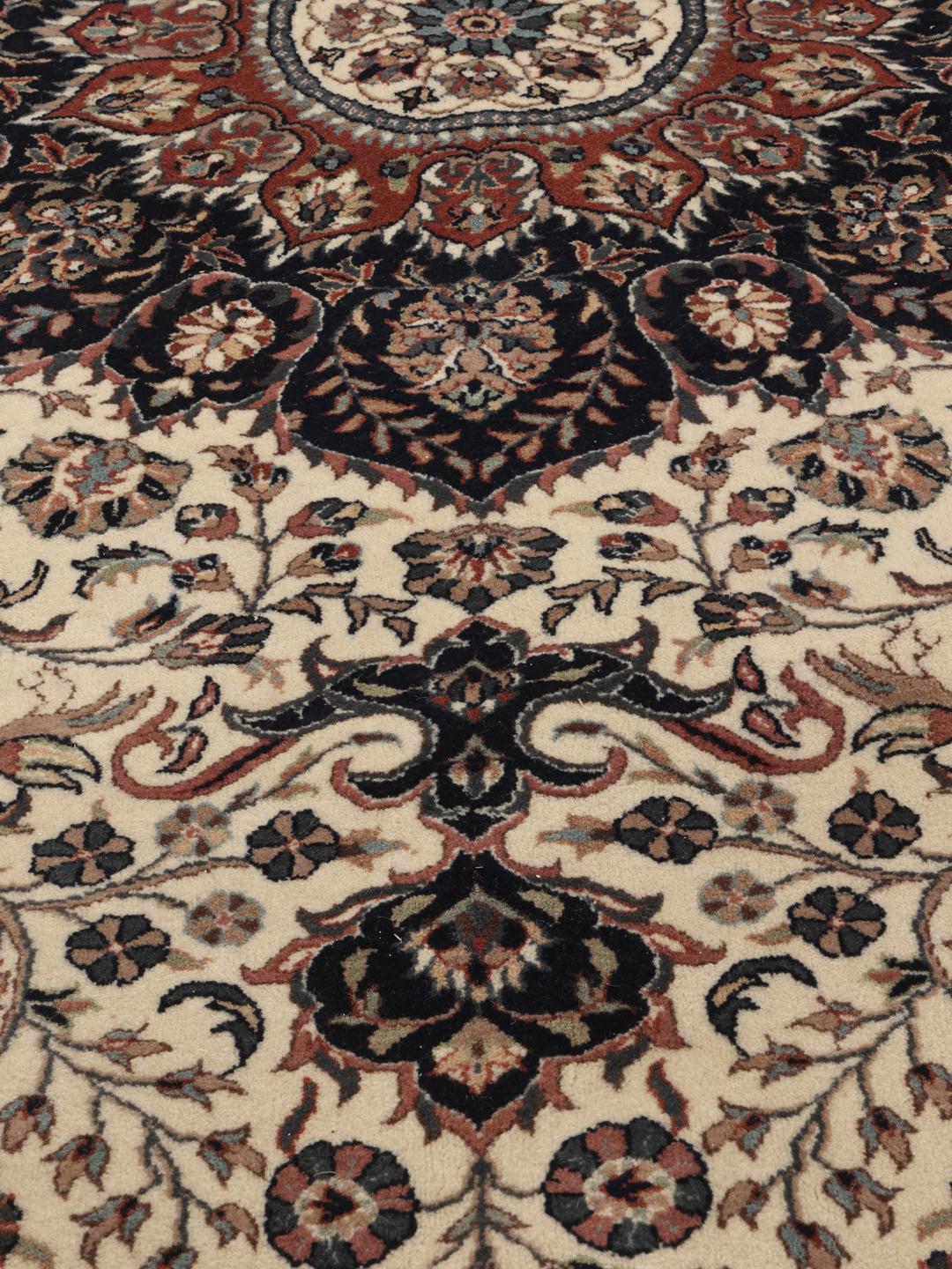 Un tapis rond Sarough American beige et bleu foncé avec des motifs floraux et un médaillon central, originaire d'Inde.