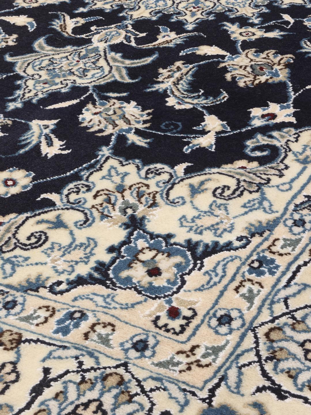 A hand-knotted Nain rug from the Middle East in dark-blue and cream tones.