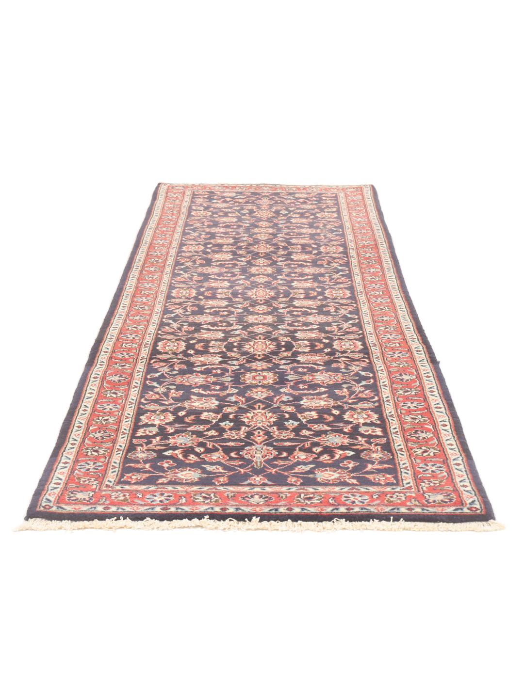 A hand-knotted Keshan runner with a dark blue field and intricate floral patterns.