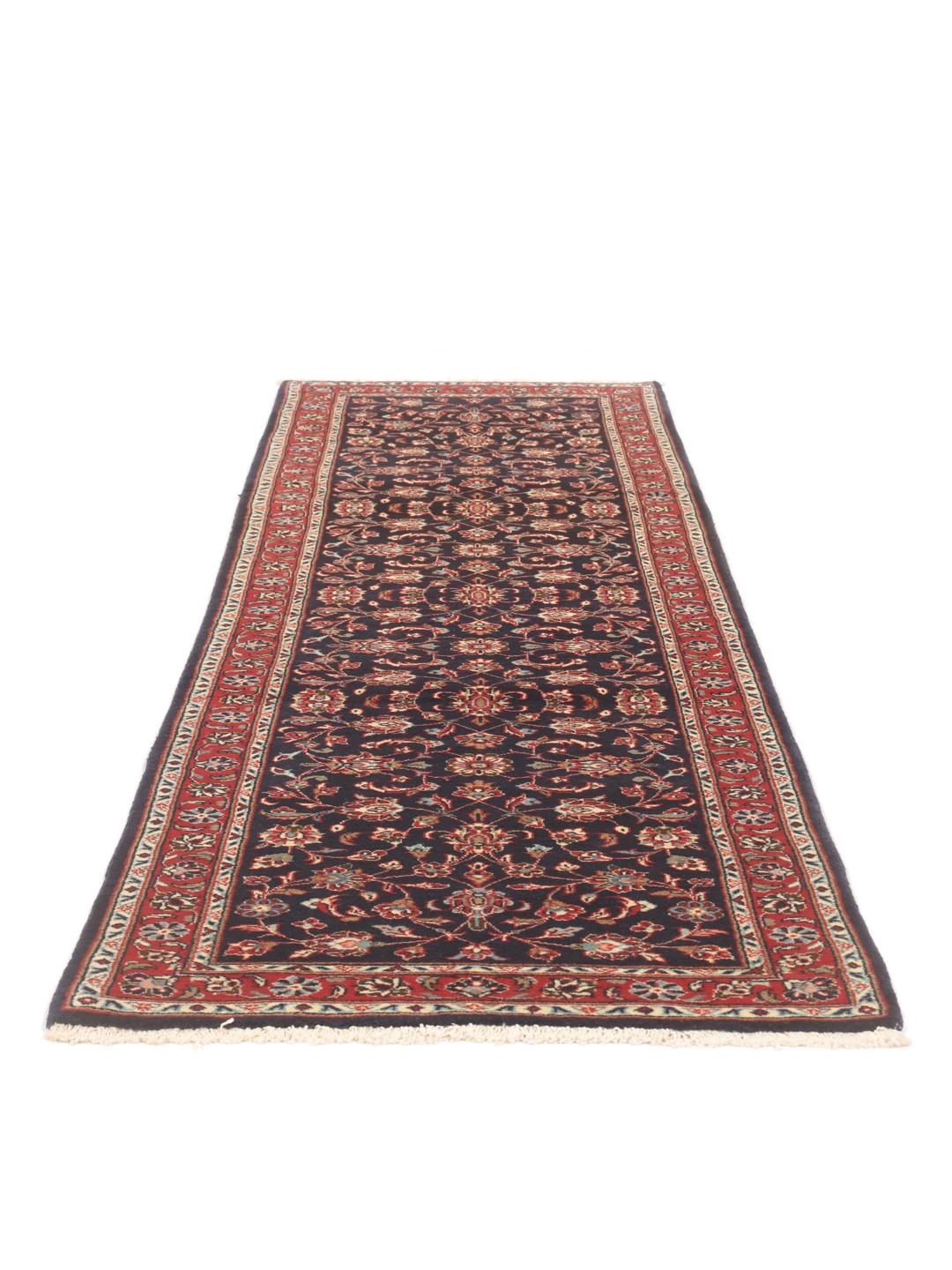 A hand-knotted Keshan runner with a dark blue field and intricate floral patterns.