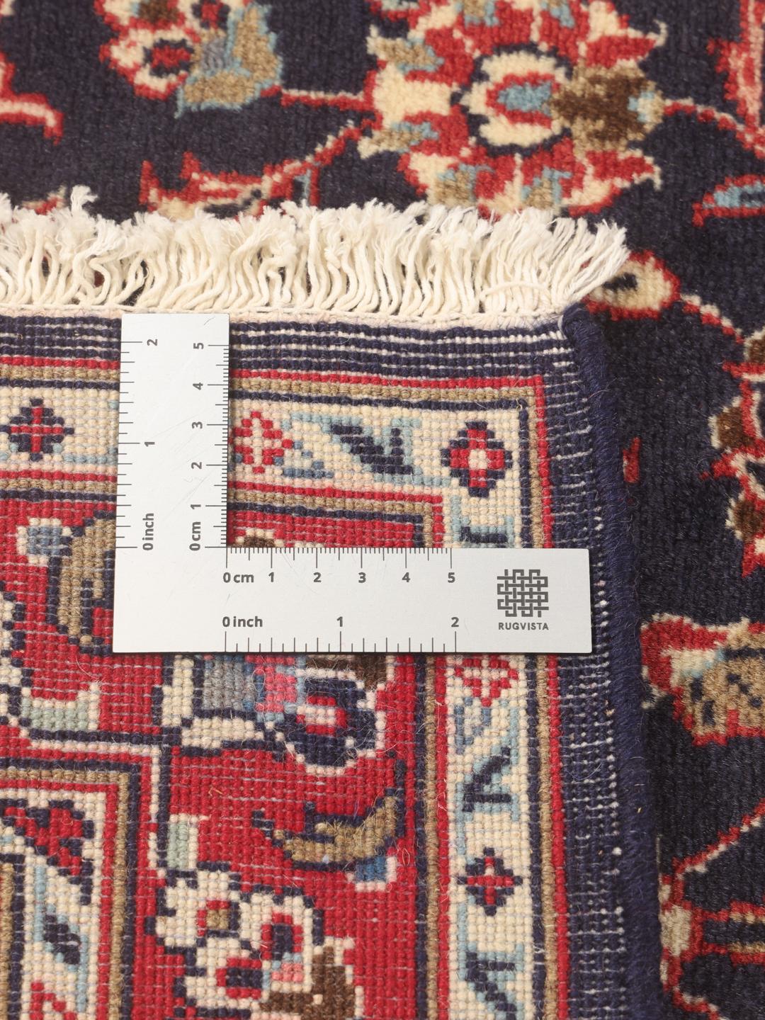 A hand-knotted Keshan runner with a dark blue field and intricate floral patterns.