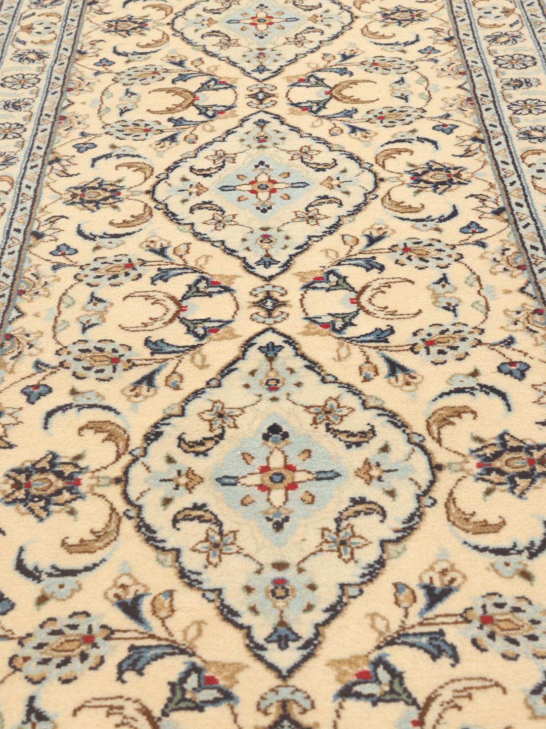 A sophisticated Keshan runner with intricate floral patterns in beige and blue from the Middle East.