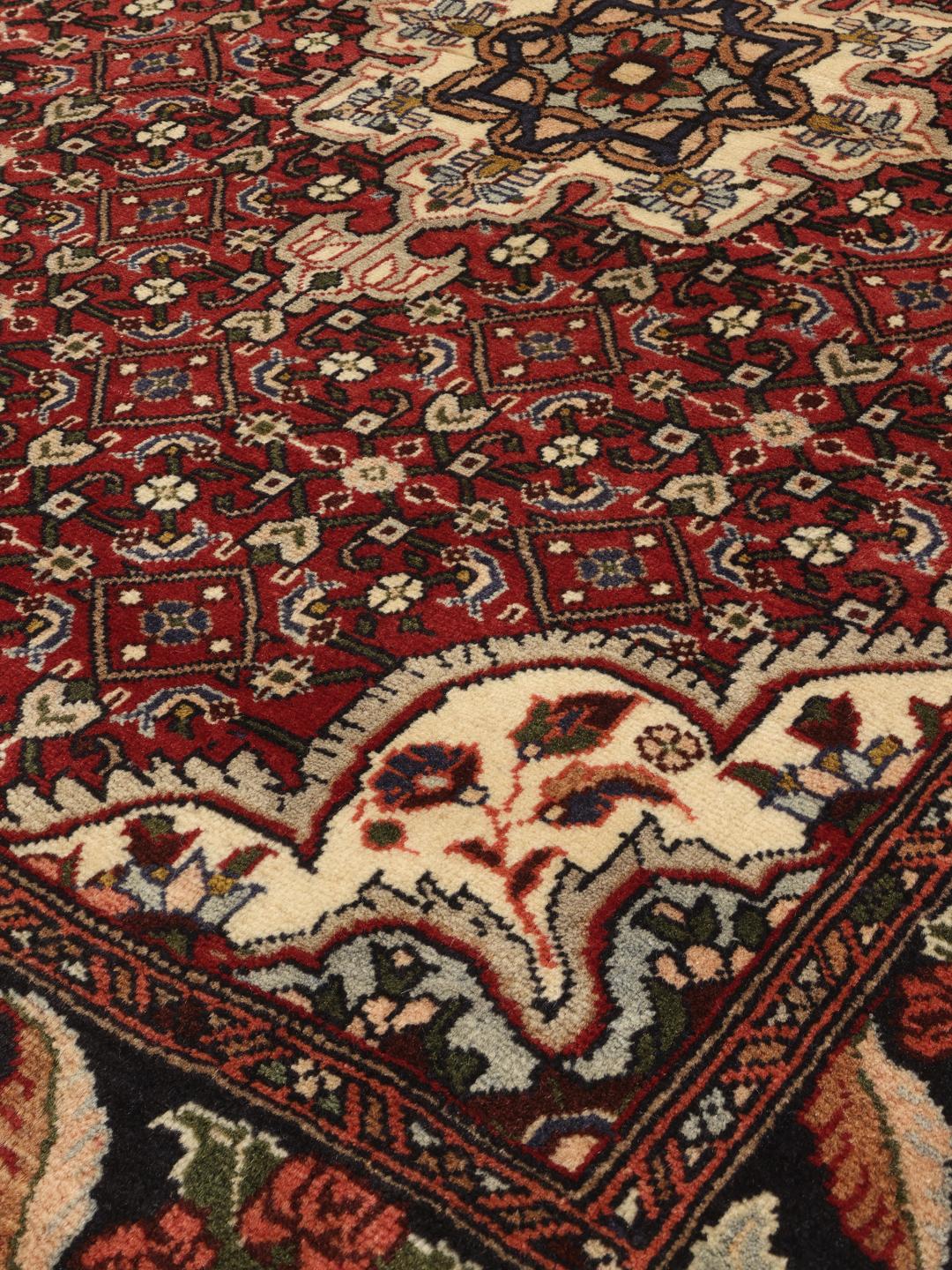 A hand-knotted Bidjar rug from the Middle East with a red field and intricate patterns.