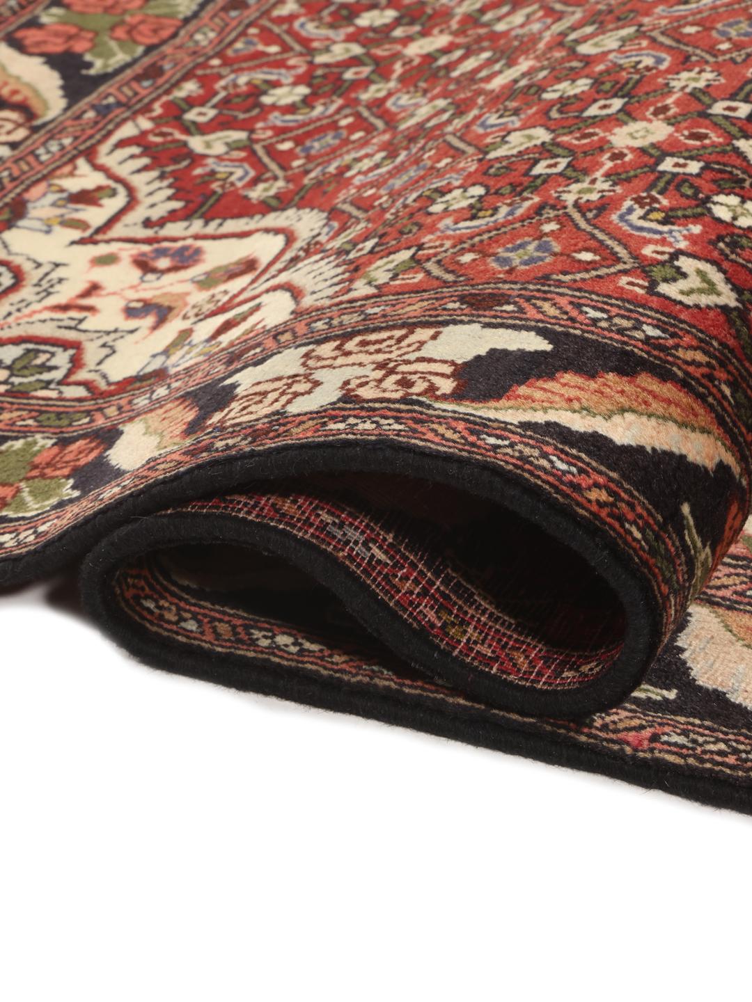 A hand-knotted Bidjar rug from the Middle East with a red field and intricate patterns.