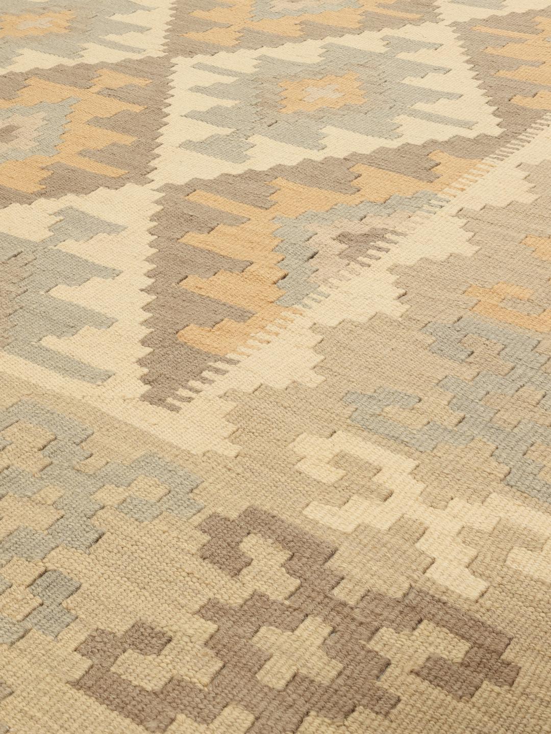 Et rektangulært håndvævet Kelim-tæppe fra Mellemøsten med et beige og flerfarvet geometrisk mønster.