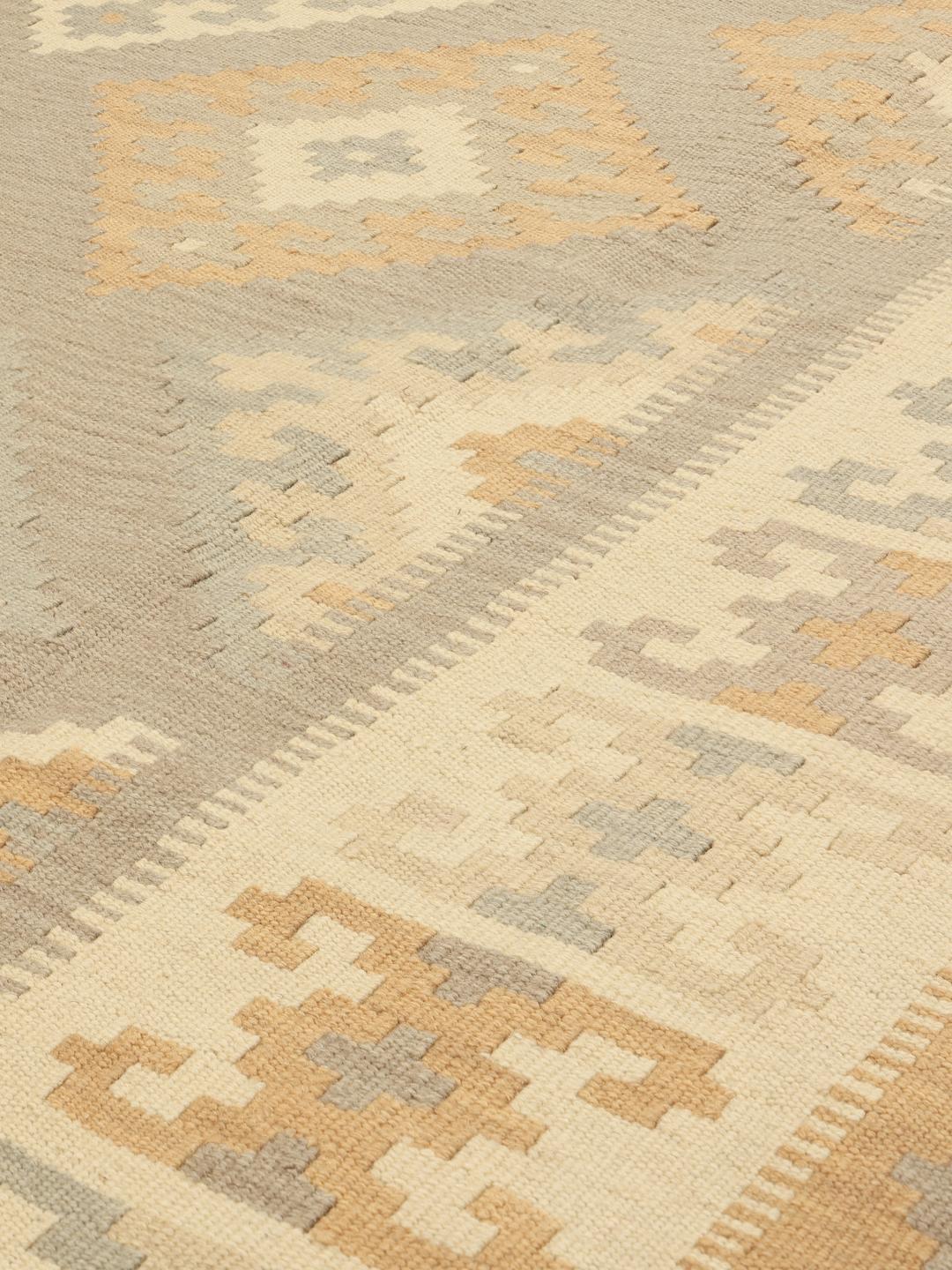 Un tappeto rettangolare Kilim Ghashghai tessuto a mano proveniente dal Medio Oriente con un motivo geometrico a rombi nei toni del beige e del grigio.