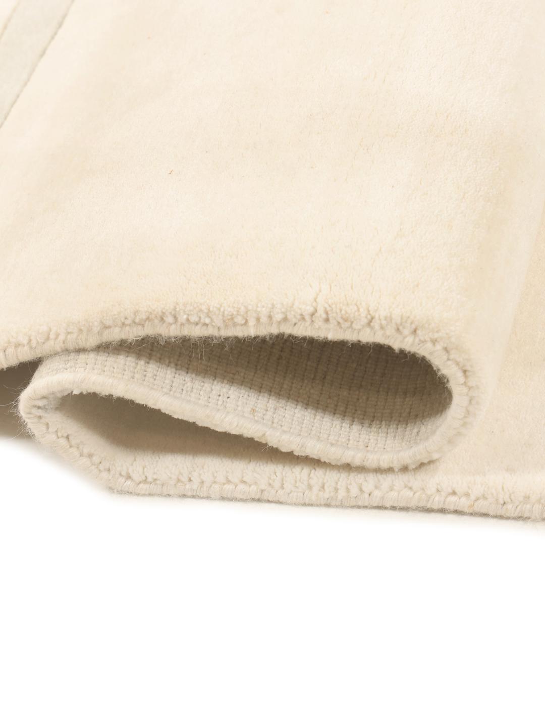 Et moderne, håndvævet tæppe fra Indien i en blød beige farve med minimalistiske stribede mønstre.