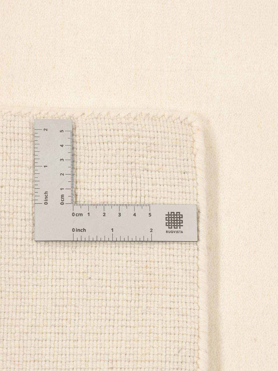 Et moderne, håndvævet tæppe fra Indien i en blød beige farve med minimalistiske stribede mønstre.