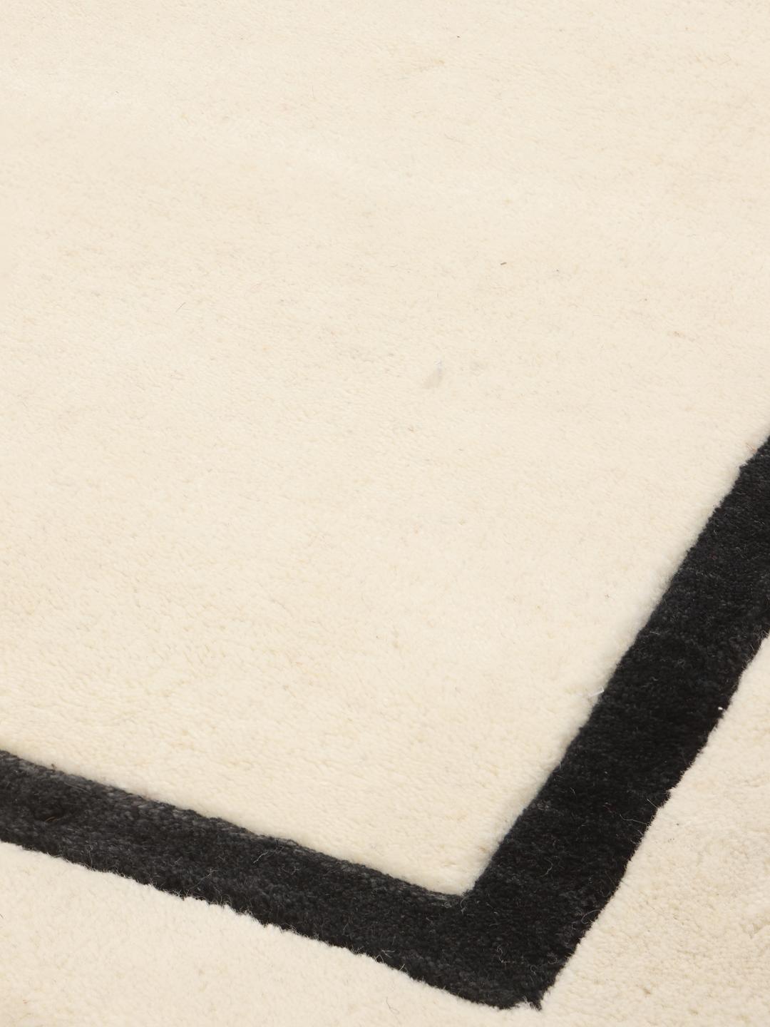 Hand-woven minimalist rug from India with a beige field and dark border