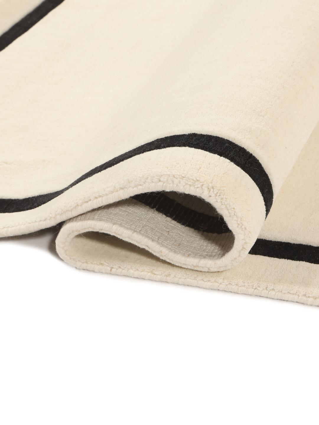 Hand-woven minimalist rug from India with a beige field and dark border