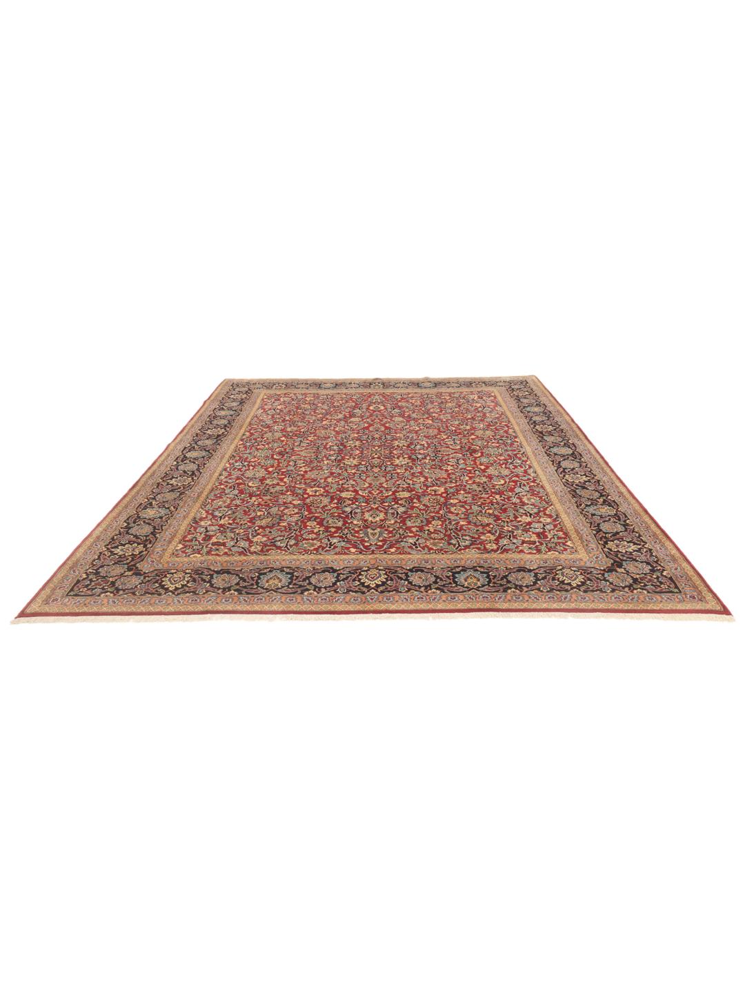 Een groot Kerman-tapijt uit het Midden-Oosten met een rood bloemmotief en een donkerblauwe rand.
