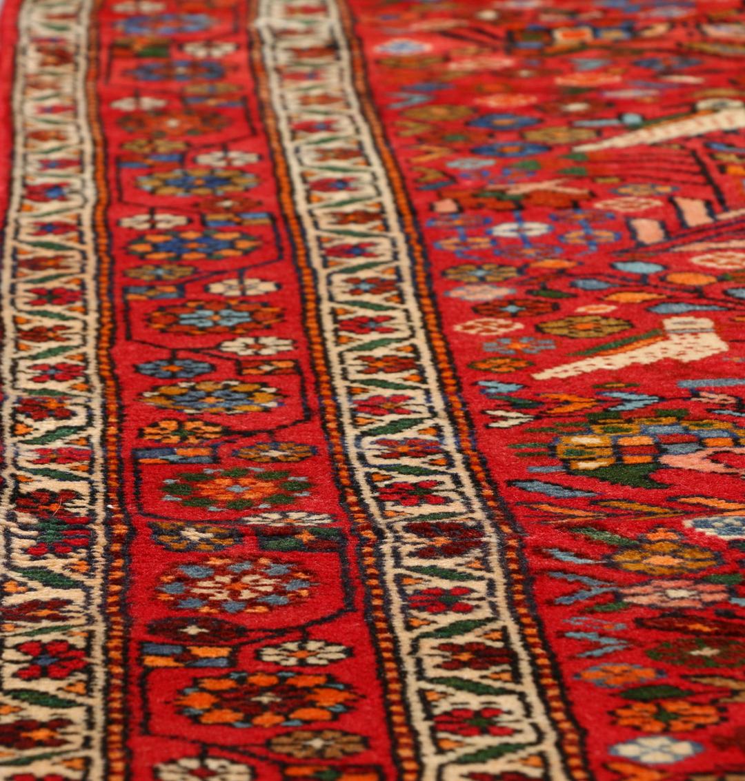 A hand-knotted Hamadan rug from the Middle East with a vibrant red field and bird motifs.