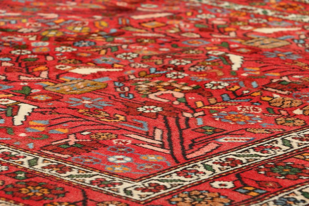 A hand-knotted Hamadan rug from the Middle East with a vibrant red field and bird motifs.