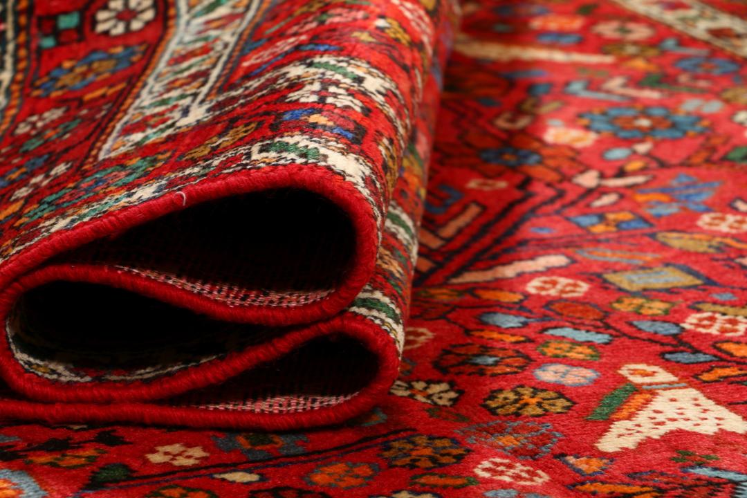 A hand-knotted Hamadan rug from the Middle East with a vibrant red field and bird motifs.