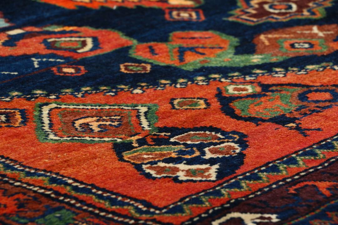 Een met de hand geknoopt Lillian-tapijt uit het Midden-Oosten met een donkerblauw en oranje kleurenpalet.