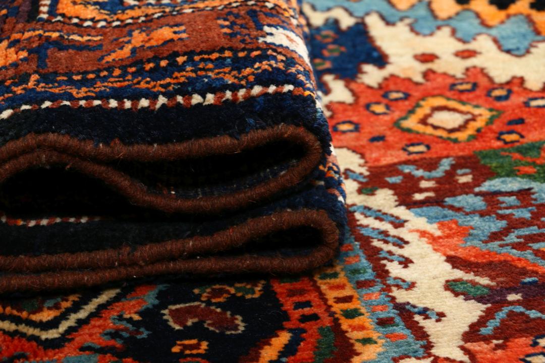Een met de hand geknoopt Lillian-tapijt uit het Midden-Oosten met een donkerblauw en oranje kleurenpalet.