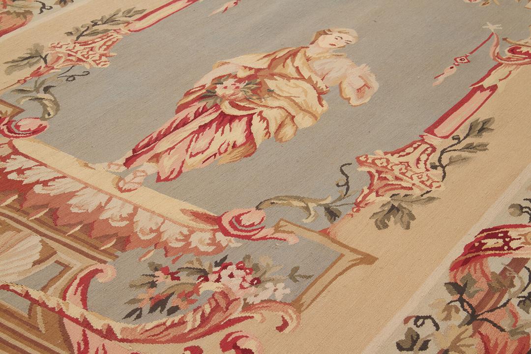 Håndvævet tæppe i Aubusson-stil med blomstermotiver og en central figur i beige og rød