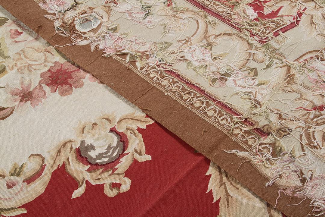 Håndvævet tæppe i Aubusson-stil med en blomstret medaljon i rød og creme, fremstillet i Kina.