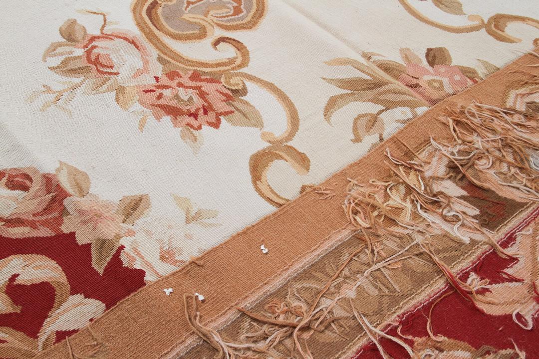 Et rektangulært håndvævet kelimtæppe med dekorative blomstermønstre i røde, elfenbensfarvede og beige toner fra Kina.