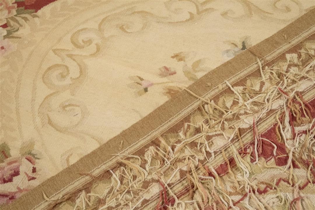Et rektangulært håndvævet kinesisk tæppe med rød baggrund og indviklede blomstermedaljon-motiver.