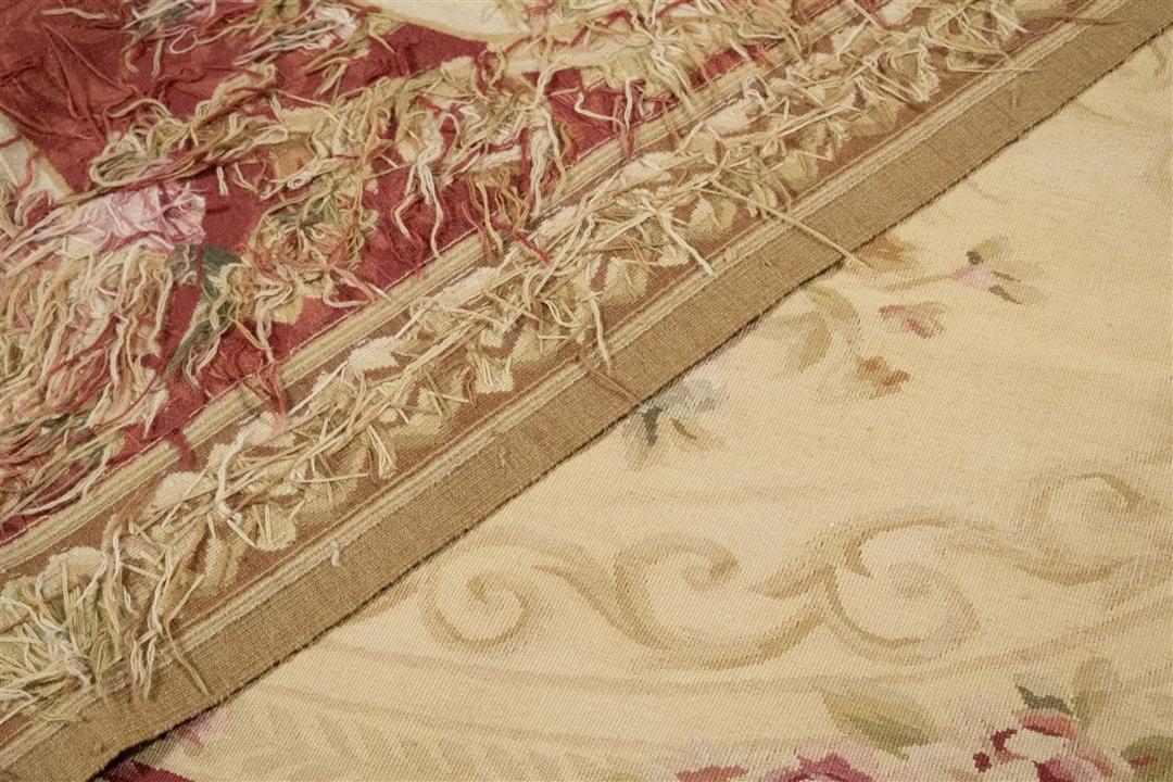 Et rektangulært håndvævet kinesisk tæppe med rød baggrund og indviklede blomstermedaljon-motiver.