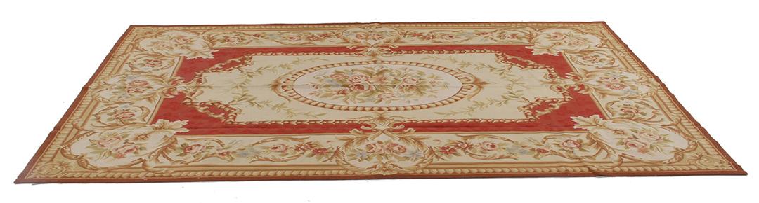 Et rektangulært håndvævet tæppe i Aubusson-stil med blomstermønstre i røde og beige toner.