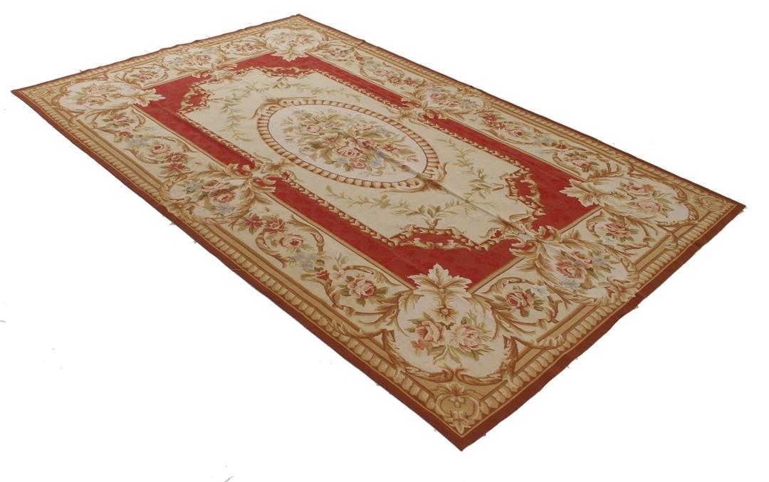 Et rektangulært, håndvævet tæppe fra Kina med et rødt og beige blomstermedaillon-design.