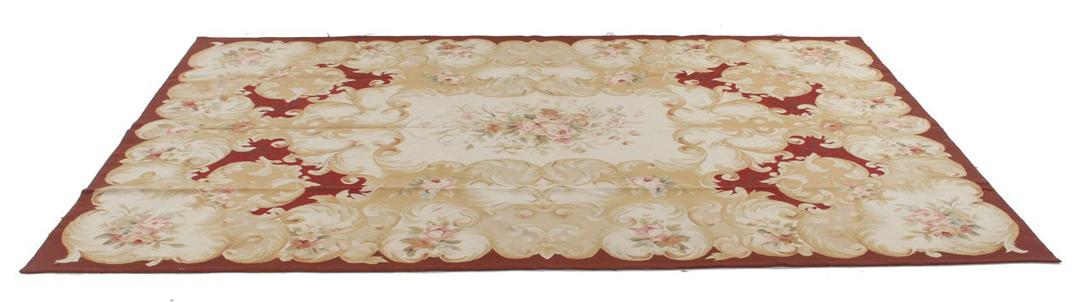 Et rektangulært, håndvævet tæppe fra Kina med et rødt og beige blomstermedaillon-design.