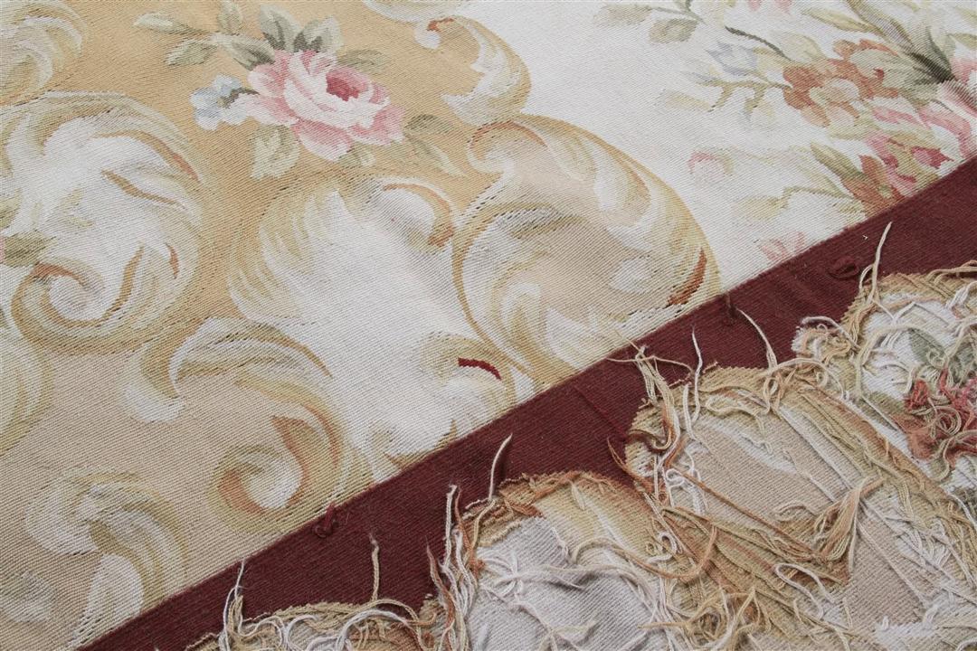 Et rektangulært, håndvævet tæppe fra Kina med et rødt og beige blomstermedaillon-design.
