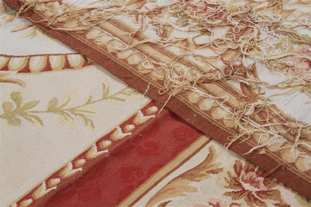 Et rektangulært, håndvævet tæppe fra Kina med et rødt og beige blomstermedaillon-design.