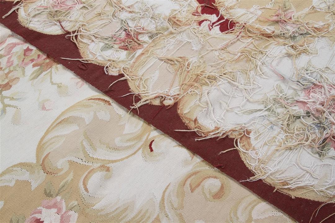 Et rektangulært håndvævet Kilim-tæppe fra Kina med et blomstermønster i rødt og beige.