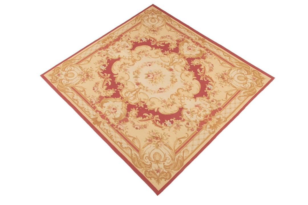 Et kvadratisk håndvævet tæppe i Aubusson-stil fra Kina med blomstermotiver i rød og beige