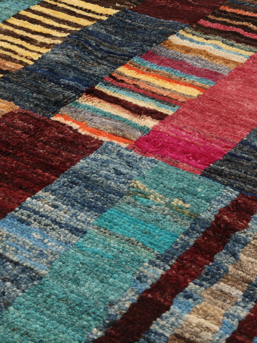 A vibrant, multicoloured, hand-knotted Afghan rug featuring a geometric block pattern.