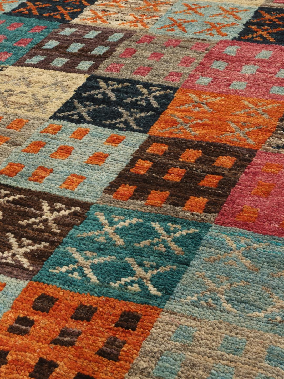 Un tapis multicolore vibrant noué à la main, originaire d'Afghanistan, avec un design patchwork géométrique.
