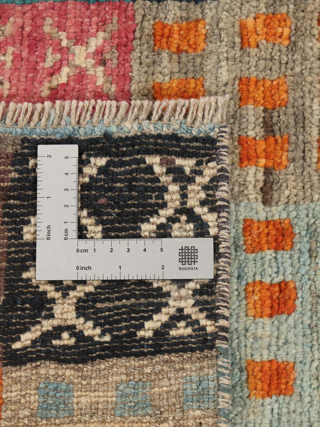 Un tapis multicolore vibrant noué à la main, originaire d'Afghanistan, avec un design patchwork géométrique.