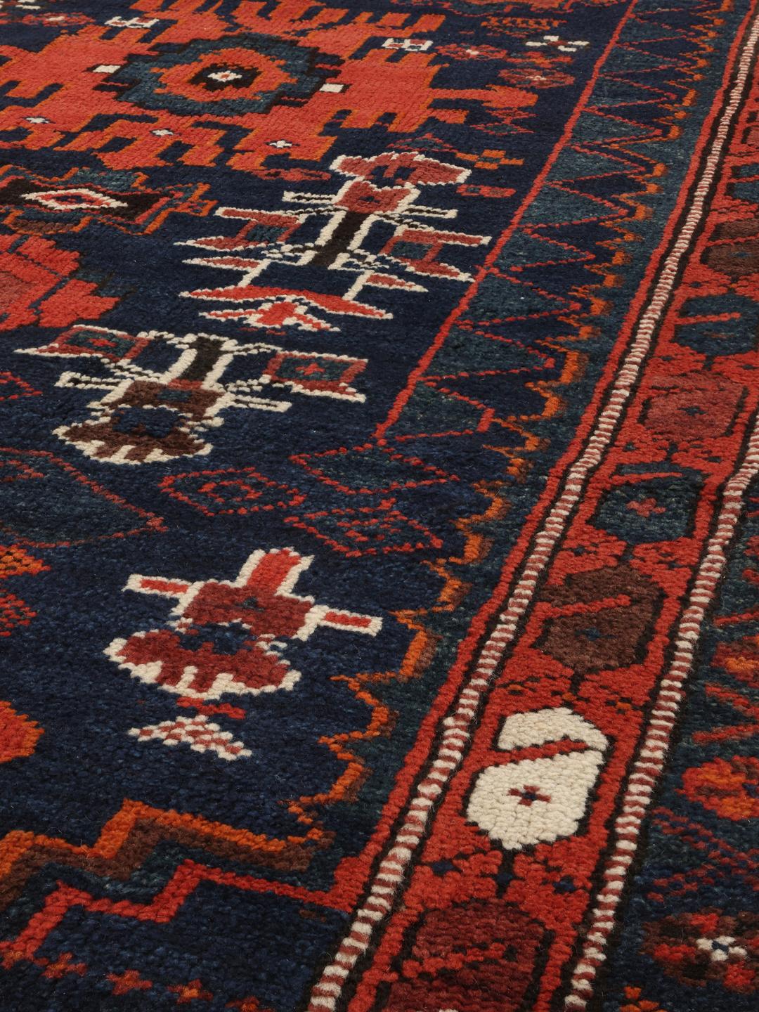 Een handgeknoopte Shiraz loper uit het Midden-Oosten met een donkerblauw en rood geometrisch ontwerp.