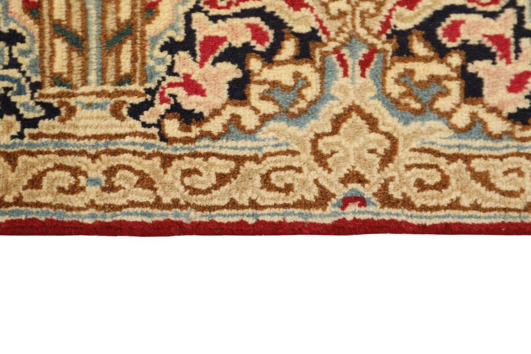 Een groot rechthoekig Kerman-tapijt uit het Midden-Oosten met een levendig rood veld en ingewikkelde bloempatronen in een decoratieve rand.
