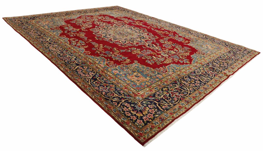 Een handgeknoopt Kerman-tapijt uit het Midden-Oosten met een rood veld en ingewikkelde bloemmotieven