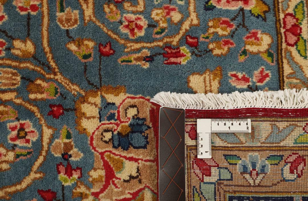 Een handgeknoopt Kerman-tapijt uit het Midden-Oosten met een rood veld en ingewikkelde bloemmotieven