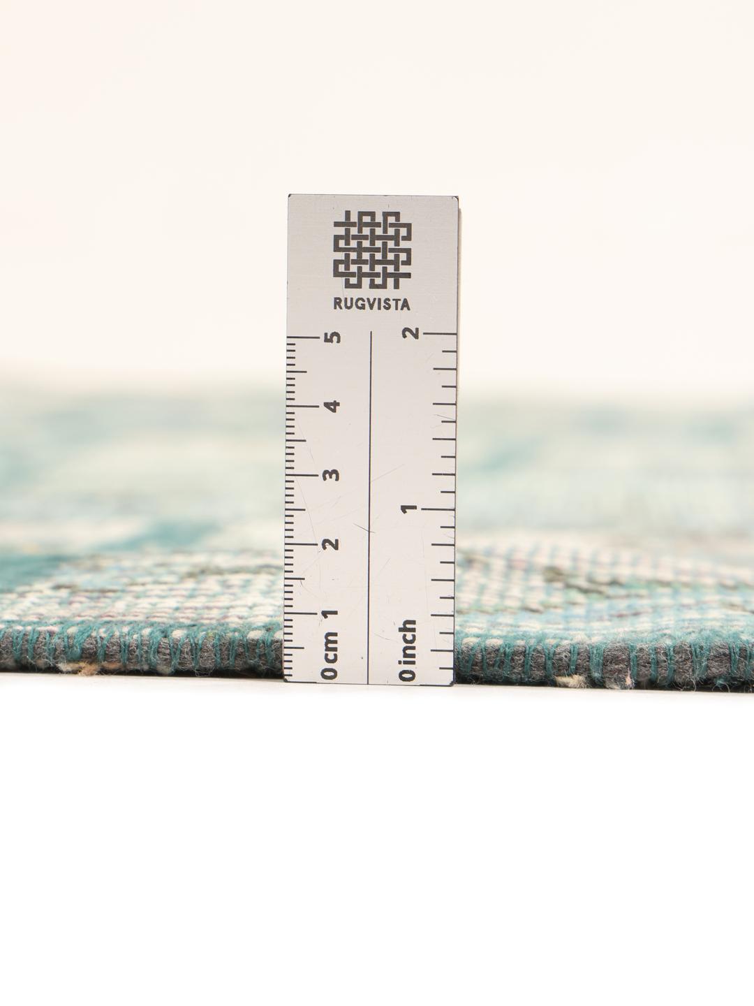 Rundt patchwork-tæppe i blå og grå nuancer med oprindelse i Mellemøsten.