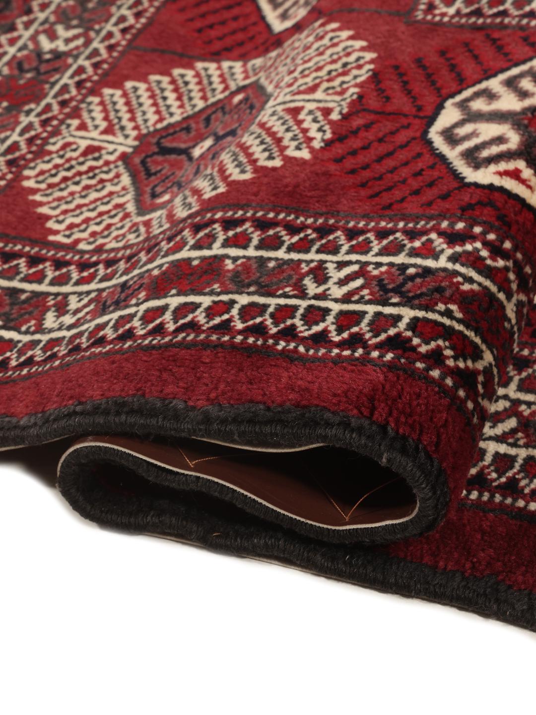 A hand-knotted Middle Eastern Turkman rug featuring deep red tones and geometric patterns.