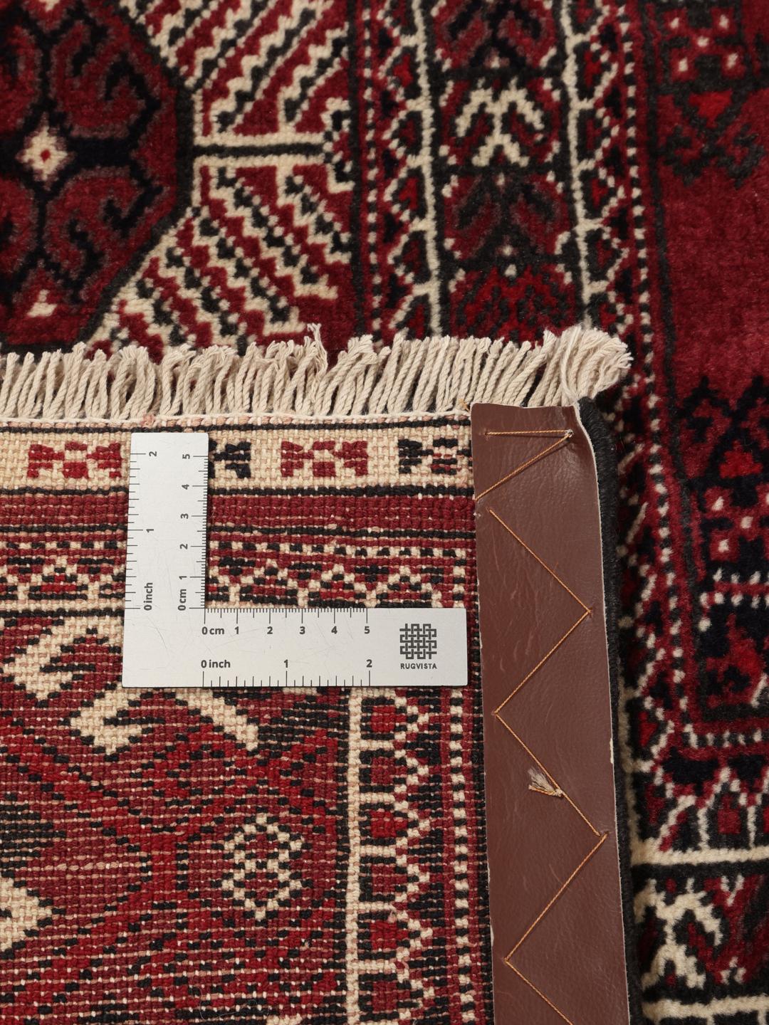 A hand-knotted Middle Eastern Turkman rug featuring deep red tones and geometric patterns.