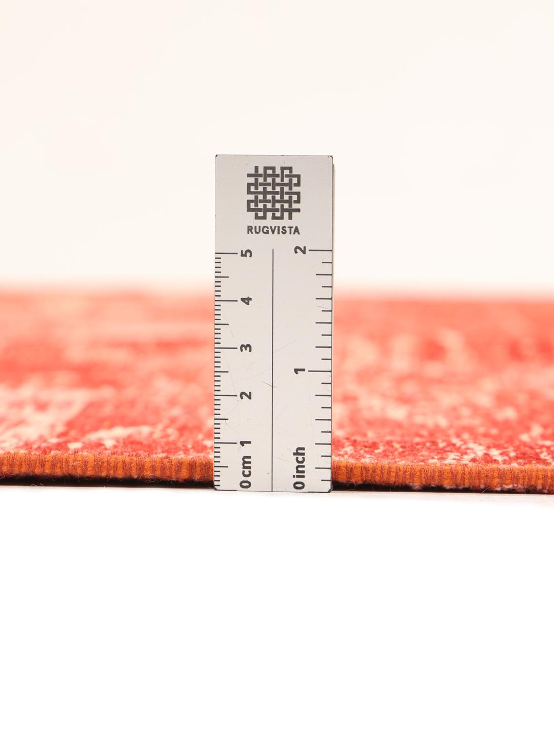 Et rundt rødt patchwork-tæppe fra Tyrkiet med et tekstureret, kunstnerisk design.