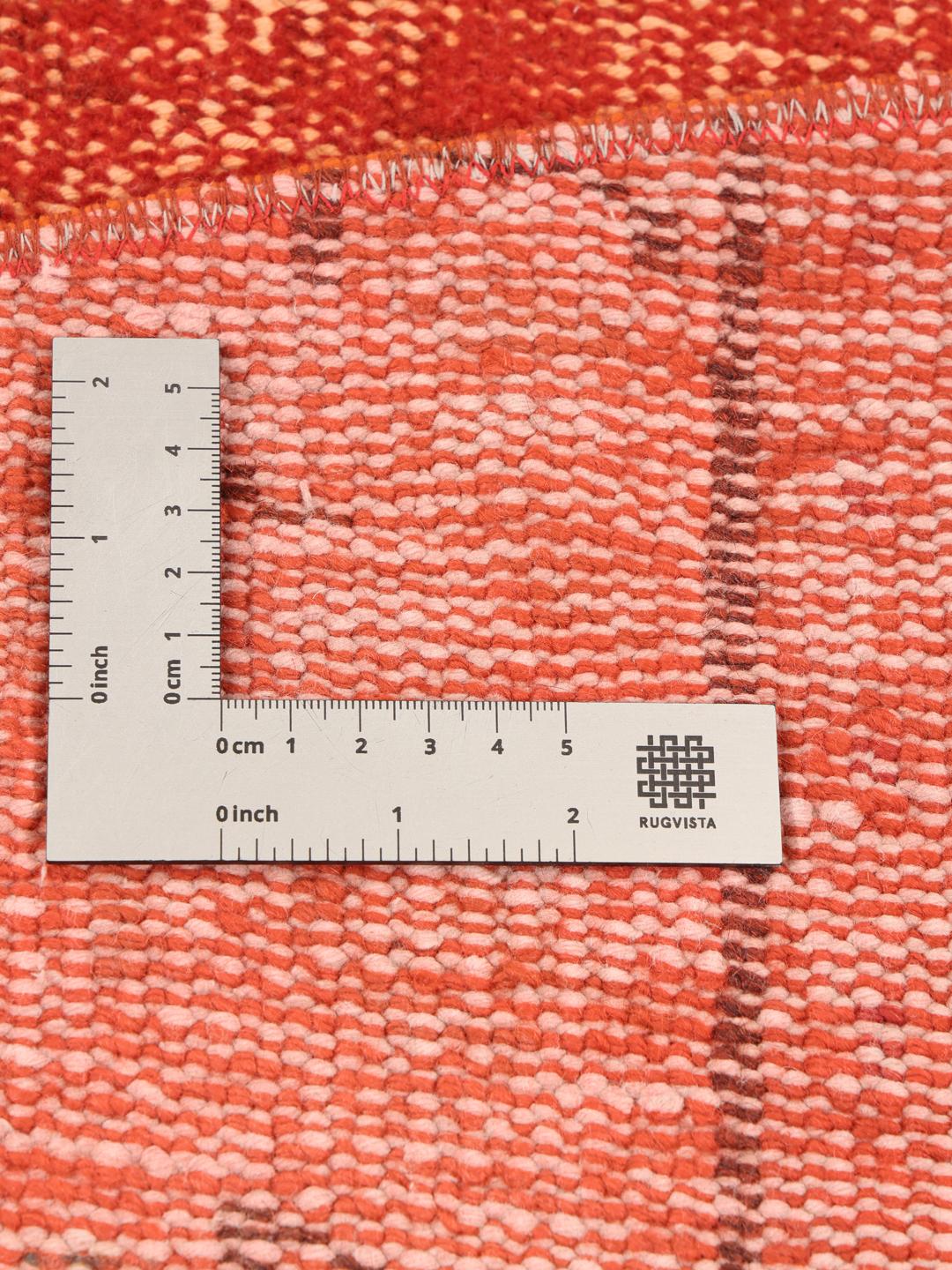 Et rundt rødt patchwork-tæppe fra Tyrkiet med et tekstureret, kunstnerisk design.