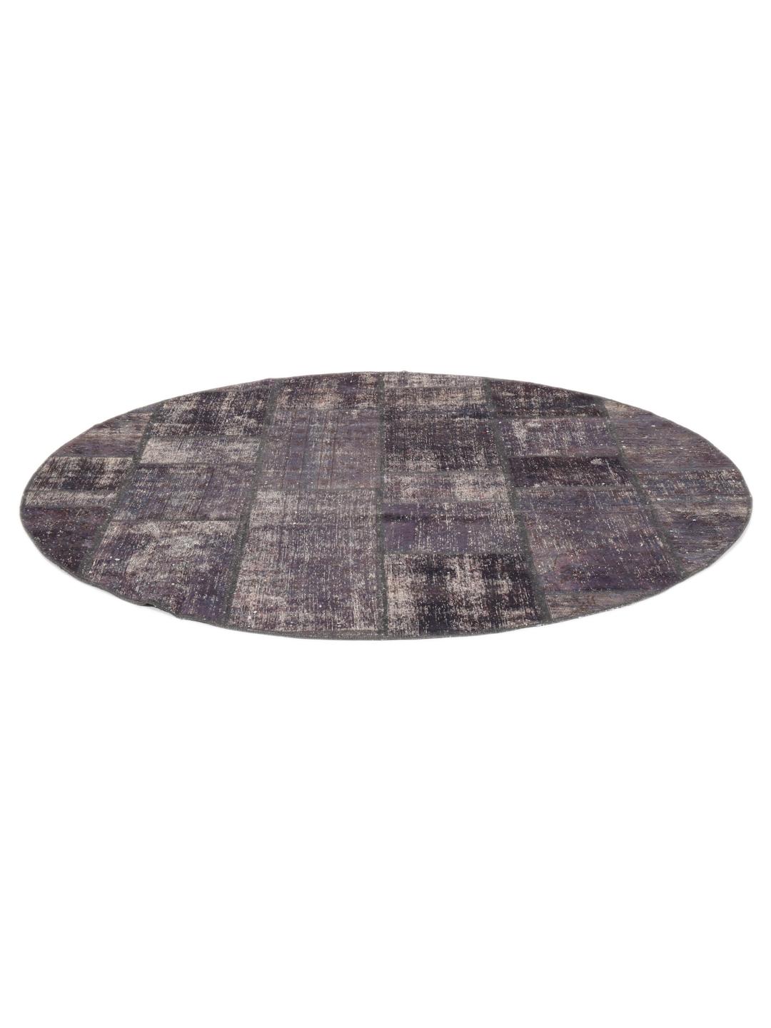Een rond patchwork vloerkleed met een donkergrijze en zwarte verweerde uitstraling
