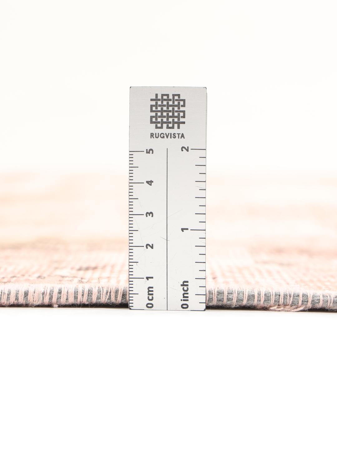 Een vierkant patchwork tapijt met zachte roze en beige tinten en vervaagde motieven uit het Midden-Oosten.