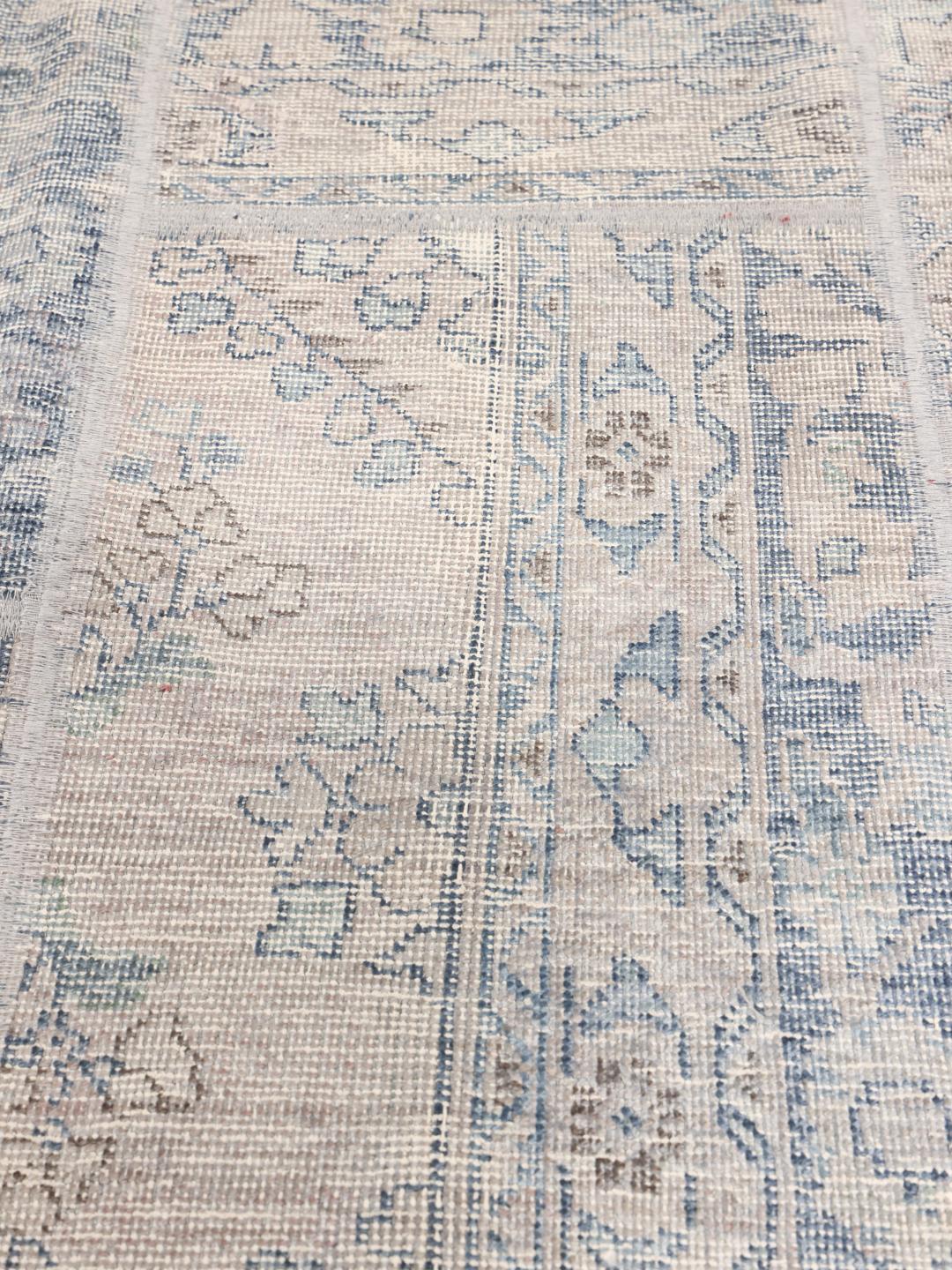 Et rundt Patchwork-teppe fra Midtøsten med en myk grå og blå palett.