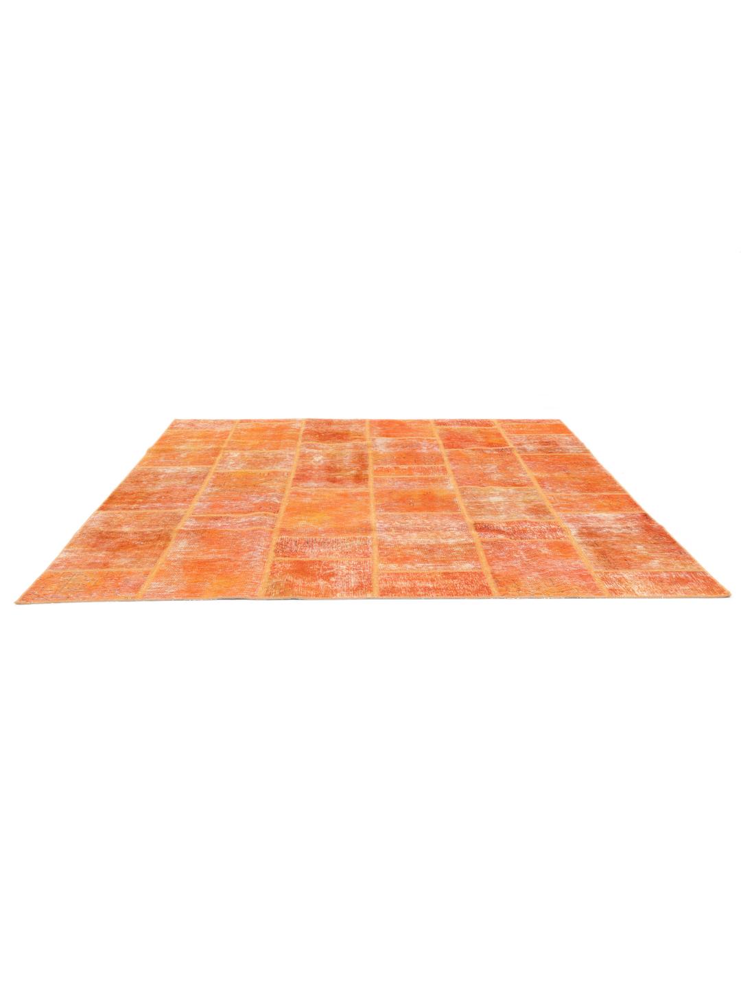 Een levendig oranje patchwork tapijt met handgeknoopte fragmenten uit het Midden-Oosten.