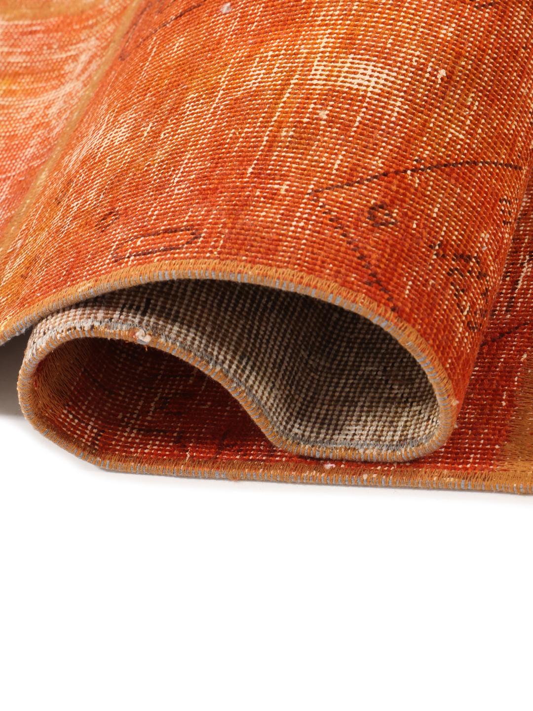 Een levendig oranje patchwork tapijt met handgeknoopte fragmenten uit het Midden-Oosten.