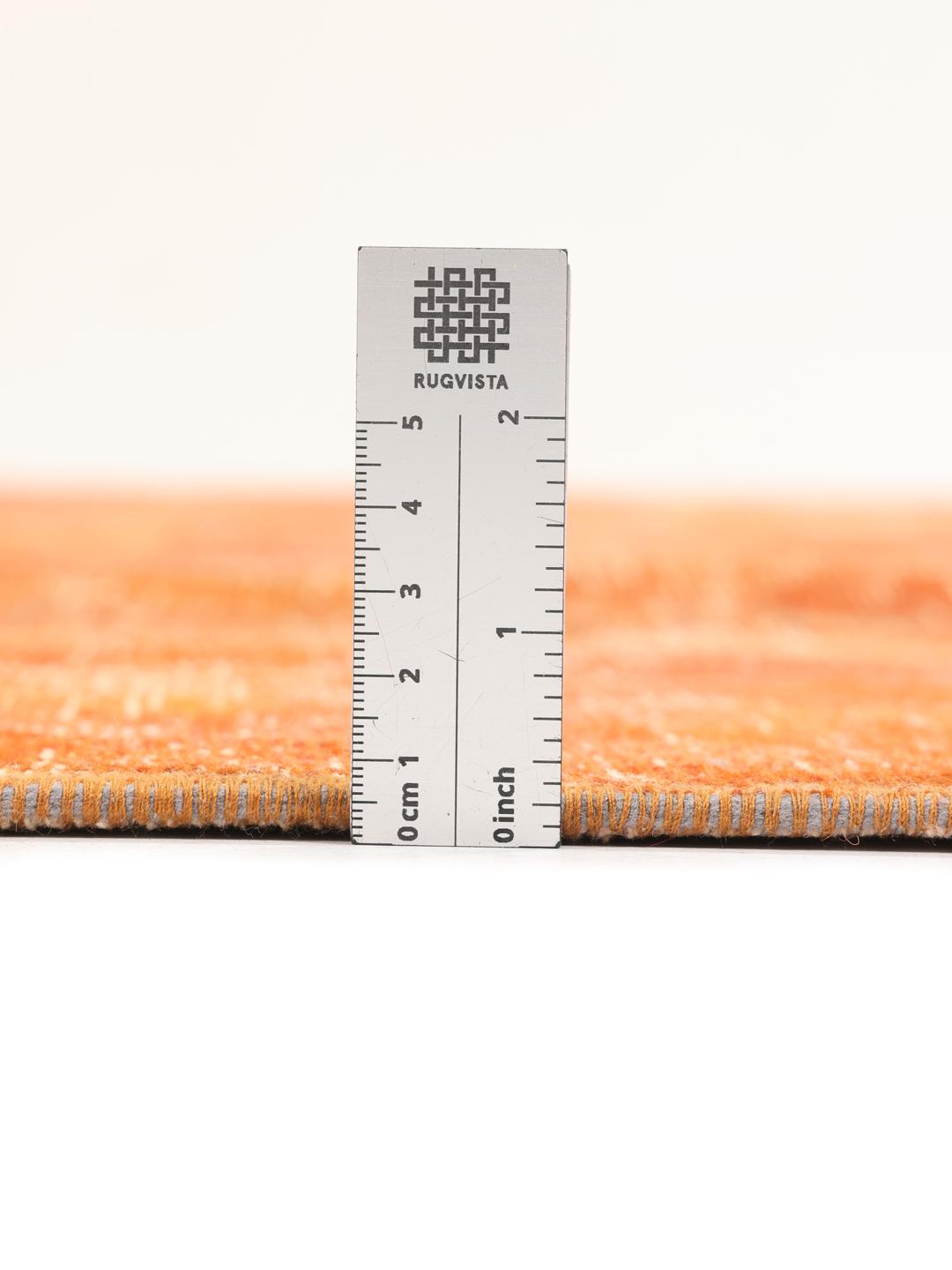 Een levendig oranje patchwork tapijt met handgeknoopte fragmenten uit het Midden-Oosten.